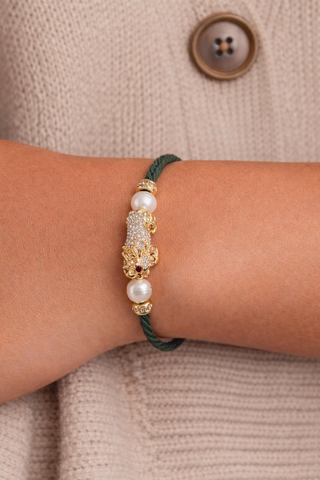 Bracelet with pearls and gold accents on a wrist against a beige sweater