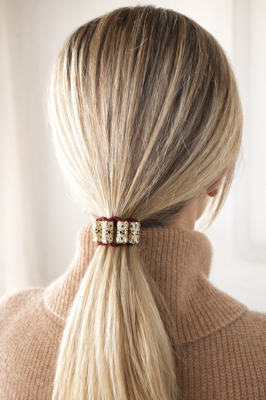 Person with blonde hair tied in a jeweled hair tie gold plated CZ burgundy cord