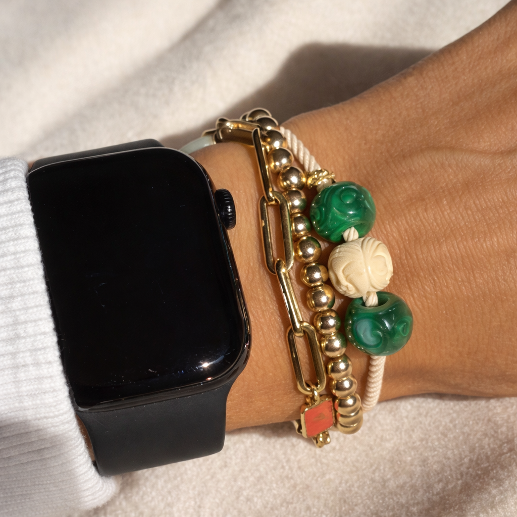 Black smartwatch on a wrist with decorative bracelets and jeweled hair tie